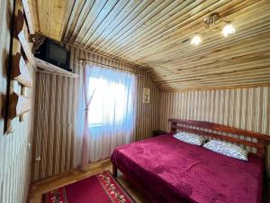 ein Schlafzimmer mit einem roten Bett und einem Fenster in der Unterkunft Гірська вершина in Slawske