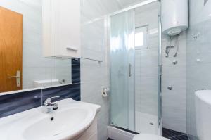 uma casa de banho branca com um lavatório e um chuveiro em Apartments Rajka em Lopar
