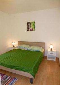 a bedroom with a bed with a green blanket on it at Apartment Ivan in Šilo