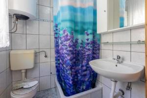 a bathroom with a sink and a blue shower curtain at Apartments Bozana in Dramalj