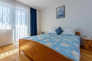 Schlafzimmer mit einem großen Bett mit blauer Decke in der Unterkunft Apartments Bozana in Dramalj