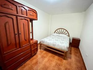 1 dormitorio con cama y tocador de madera en Departamento completo a minutos de playas, en Barranca