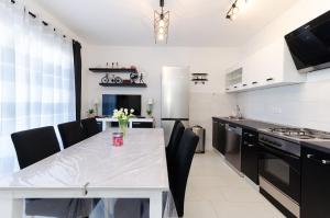 a kitchen with a white table and black appliances at Apartment Marica Sanja in Palit +17 photos