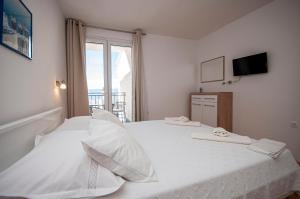 Schlafzimmer mit einem großen weißen Bett und einem Fenster in der Unterkunft Apartments and Rooms Nikola in Omiš
