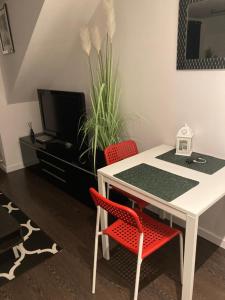 uma sala de jantar com uma mesa branca e 2 cadeiras vermelhas em Apartament Trocera em Zabrze