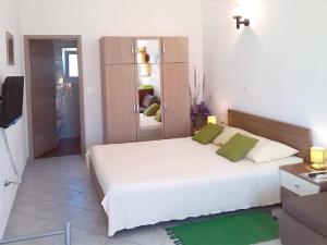 a bedroom with a large white bed with green pillows at Apartment Branko in Sutomišćica