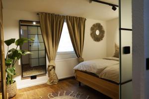 1 dormitorio con cama, espejo y ventana en Pfalzkind - Ein Stück Heimat im Alltag, en Bad Dürkheim