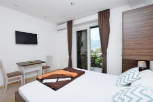 1 dormitorio con cama, escritorio y ventana en Apartments Ivanovic, en Budva