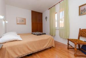 a bedroom with a bed and a chair and a window at Apartment Aljosa in Bol