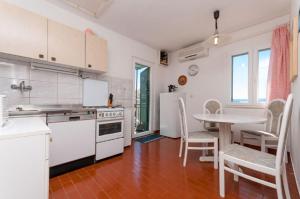 una cucina con elettrodomestici bianchi e tavolo con sedie di Apartment Aljosa a Bol