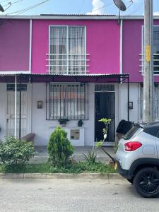 une maison rose avec une voiture garée devant elle dans l'établissement Casa Familiar Pereira Manzana, à Pereira