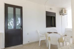 a white dining room with a table and white chairs at Apartments Aleksandar in Ulcinj