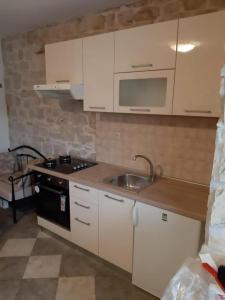 Una cocina con gabinetes blancos, un fregadero y una estufa. en Apartments Anita, en Slatine