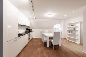 uma cozinha com armários brancos e uma mesa e cadeiras em AirHome - Raekoja Plats em Talin