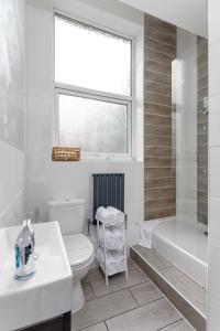 a bathroom with a toilet and a tub and a window at Snuggle Cove Apartments By Bella Vita Stays in Liverpool