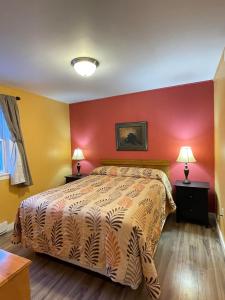 Fair Isle Motel في شارلوت تاون: غرفة نوم بسرير وجدار احمر