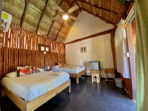 a bedroom with two beds and a tv in it at Cabañas Frida in Chelem