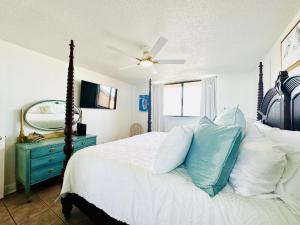 - une chambre avec un lit, une commode bleue et un miroir dans l'établissement Gulf Front Penthouse Condo, à Pensacola Beach