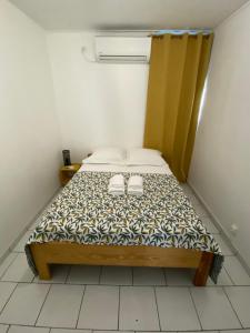 Un pequeño dormitorio con una cama con dos zapatos. en Appartement moderne, 2 chambres, proche aéroport • CHU • port, en Les Abymes