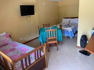 a room with two beds and a table and a tv at Estalagem O Italiano in Lumiar