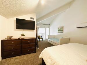 a bedroom with a bed and a dresser with a flat screen tv at Gulf Front Penthouse Condo in Pensacola Beach