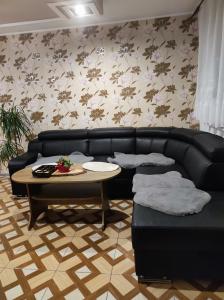 a living room with a black leather couch and a table at Ubytovňa Ivona in Hroboňovo