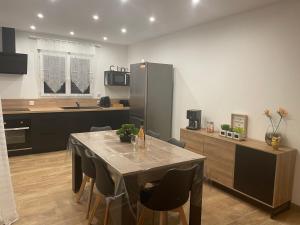a kitchen with a table with chairs and a refrigerator at Les oiseaux du paradis in Saint-Aignan +15 photos