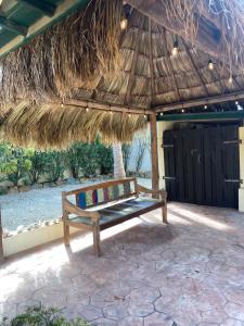 a wooden bench under a straw umbrella on a patio at Casa Opal in Palm-Eagle Beach