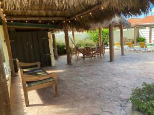 um pátio com um guarda-sol de palha, cadeiras e mesas em Casa Opal em Palm-Eagle Beach