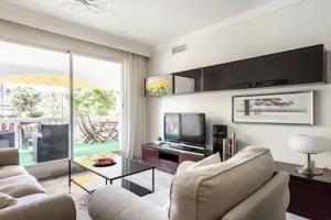 een woonkamer met een bank en een televisie bij Apartamento Dama de Noche Marbella in Marbella