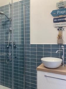 a bathroom with a sink and a shower with blue tiles at 27 boulevard Féart in Dinard