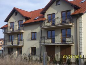 un edificio con balcones y techo rojo en Apartamenty by Hanna, en Łeba