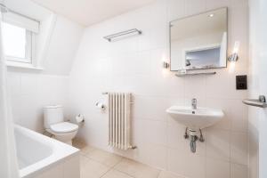 a white bathroom with a sink and a toilet at Hotel Jacobs in Bruges