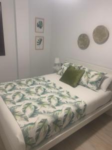 a bed with a green and white blanket and pillows at Gosol Lemon in Sanlúcar de Barrameda