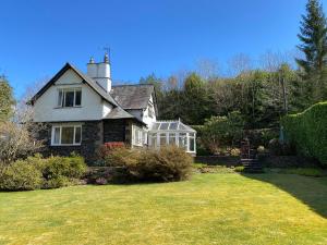 an old house with a lawn in front of it at Brunton Lodge in Bowness-on-Windermere