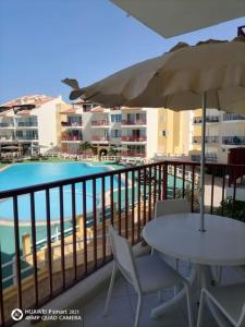 a balcony with a table and an umbrella and a pool at Solaren Apartments Boavista in Sal Rei
