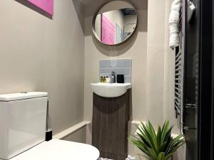 a bathroom with a sink and a toilet and a mirror at University Apartment • Sleeps 8 in Loughborough