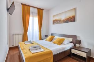a bedroom with a large bed with a yellow blanket at Garni Hotel Milica in Herceg-Novi