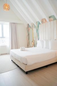 a white bedroom with a large bed with white pillows at Harbor Hotel & Casino Curacao in Willemstad