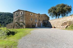 un antiguo edificio de piedra con una carretera delante de él en B&B Can Jan en Sant Ferriol