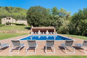 a pool with chairs and a house in the background at B&B Can Jan in Sant Ferriol