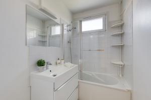 a white bathroom with a sink and a shower at Spacieux 3 pièces Paris / Disney in Noisy-le-Grand