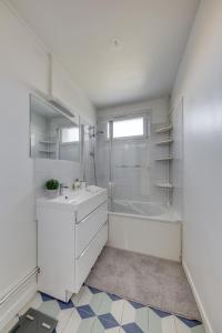 a white bathroom with a tub and a sink at Spacieux 3 pièces Paris / Disney in Noisy-le-Grand