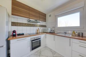 a kitchen with white cabinets and a window at Spacieux 3 pièces Paris / Disney in Noisy-le-Grand
