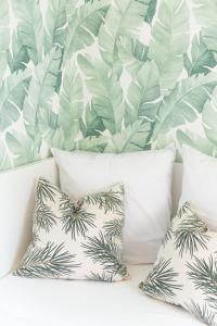 a group of pillows on a couch with a tropical wallpaper at Spacieux 3 pièces Paris / Disney in Noisy-le-Grand
