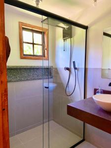a bathroom with a glass shower and a sink at Estação Andorinhas Ibitipoca in Lima Duarte
