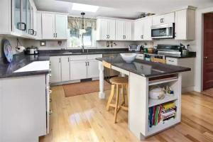 een keuken met witte kasten en een zwart aanrecht bij STILLWATER LODGE LIMIT 10 home in Windham