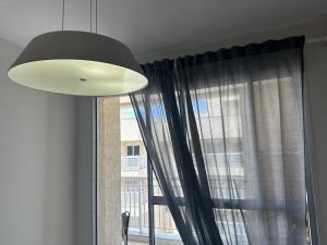 a light fixture and a window with curtains at Mediterrâneo 507 - Todo Equipado, Ar Condicionado, Churrasqueira na Varanda, Internet Fibra 600MB, Estacionamento Grátis in Cabo Frio