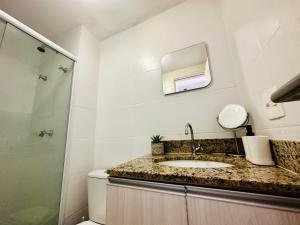 a bathroom with a sink and a shower and a mirror at Mediterrâneo 507 - Todo Equipado, Ar Condicionado, Churrasqueira na Varanda, Internet Fibra 600MB, Estacionamento Grátis in Cabo Frio