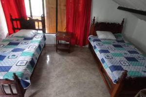 twee bedden in een kamer met rode gordijnen bij Finca la cristalina in Moniquirá